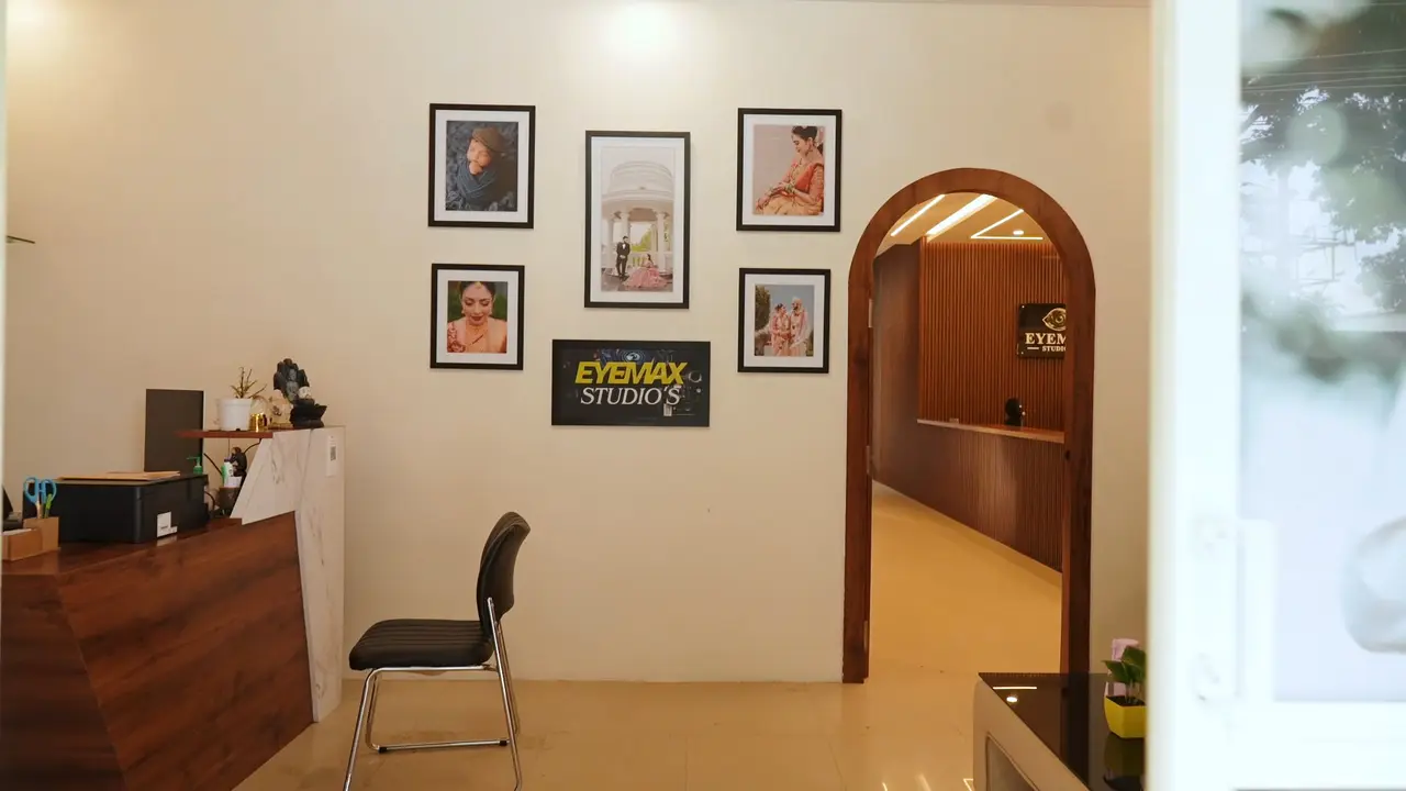 Inside Eyemax Studios: framed portraits and the studio's sign on a cream wall, a wooden front desk and an arched doorway